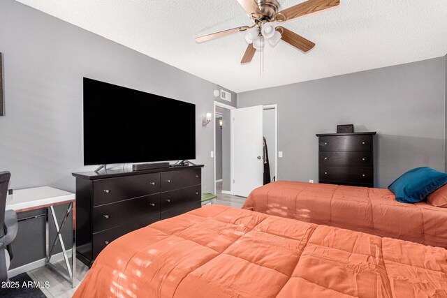 bedroom with hardwood / wood-style flooring, ceiling fan, and a textured ceiling