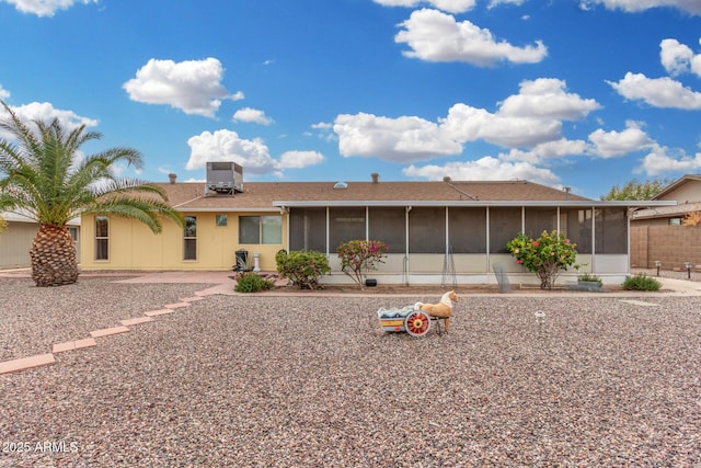 rear view of house with central AC and a sunroom