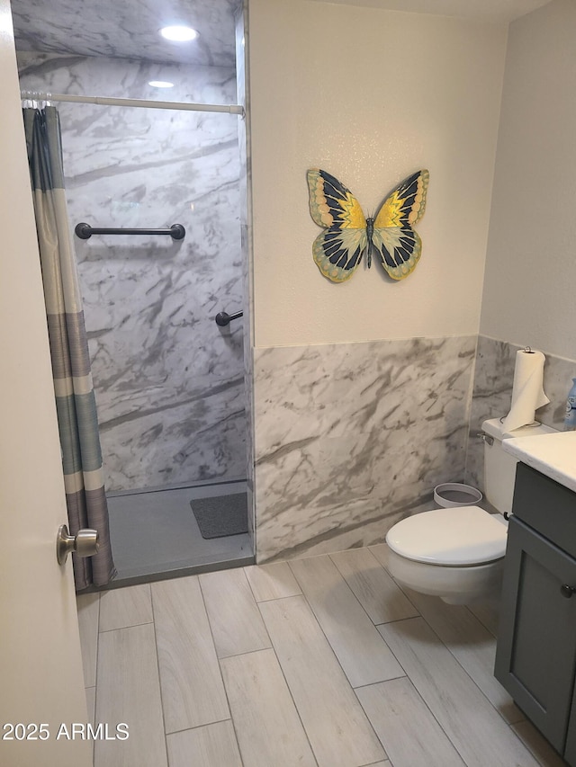 bathroom featuring vanity, tile walls, toilet, and walk in shower