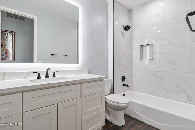 full bathroom featuring tiled shower / bath, hardwood / wood-style floors, vanity, and toilet