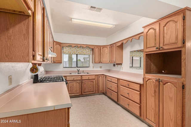 kitchen featuring gas range oven, light tile patterned floors, and sink