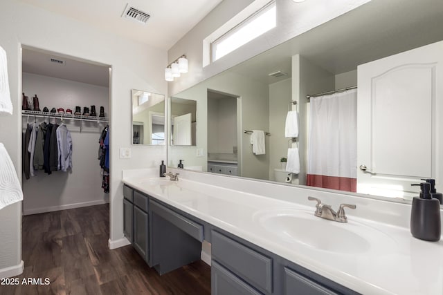 bathroom with double vanity, wood finished floors, visible vents, and a sink