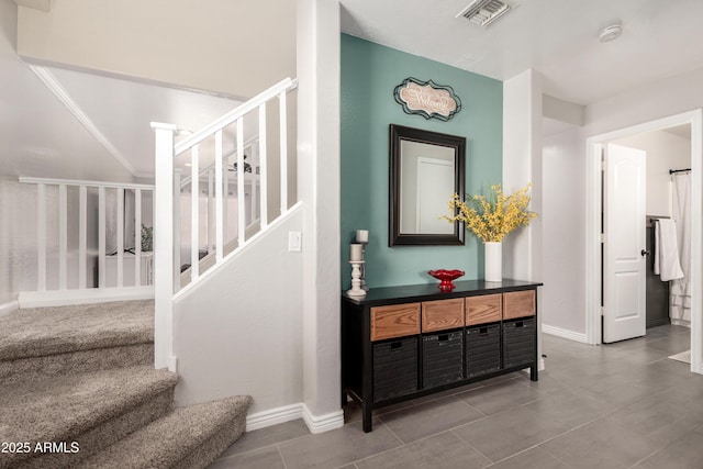 stairway with visible vents, tile patterned flooring, and baseboards