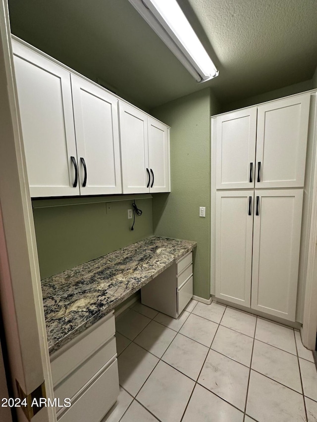 washroom featuring a textured ceiling and light tile patterned floors