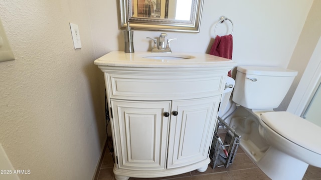 bathroom with vanity, toilet, and a textured wall