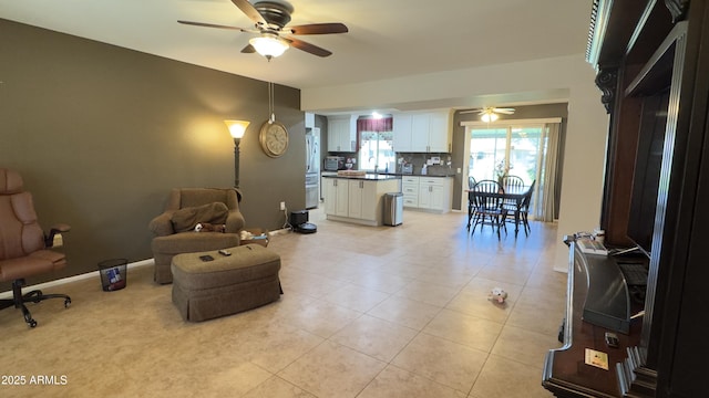 sitting room featuring light tile patterned flooring, baseboards, and ceiling fan