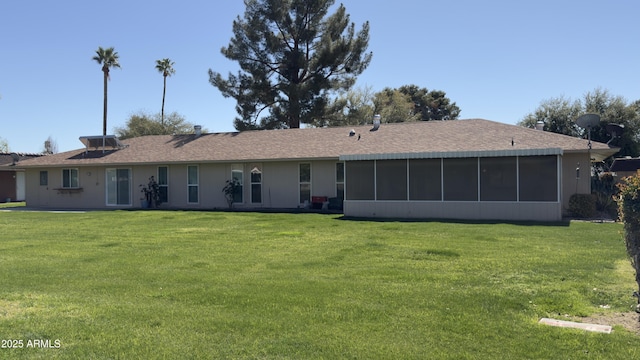 back of property with a lawn, a shingled roof, and a sunroom