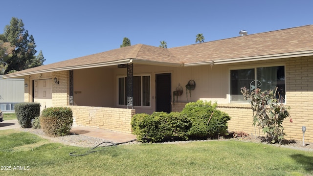 view of front of house with brick siding, a front yard, and roof with shingles