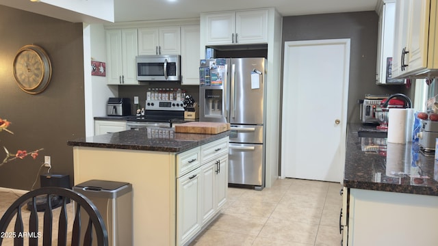 kitchen with white cabinets, light tile patterned flooring, a kitchen island, and stainless steel appliances