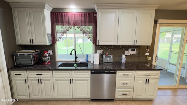 kitchen featuring a sink, a healthy amount of sunlight, dark stone counters, and stainless steel dishwasher