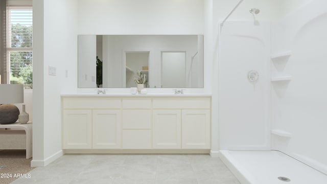 full bathroom with tile patterned flooring, baseboards, walk in shower, double vanity, and a sink