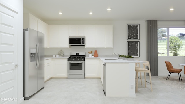 kitchen featuring a sink, stainless steel appliances, a kitchen breakfast bar, and white cabinetry