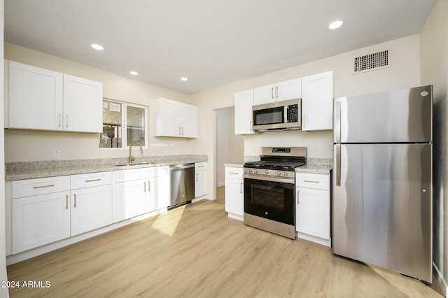 kitchen with sink, white cabinets, stainless steel appliances, and light wood-type flooring