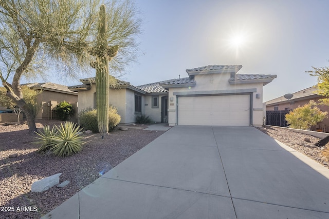 view of front of home with driveway, an attached garage, a tiled roof, and stucco siding