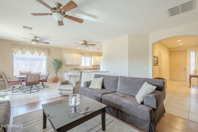 living room featuring arched walkways, a wealth of natural light, and visible vents