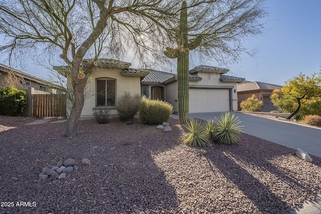 view of front facade with stucco siding, an attached garage, fence, driveway, and a tiled roof