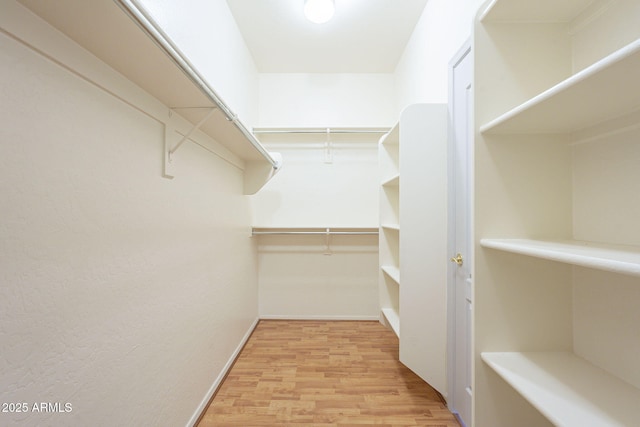 walk in closet with wood finished floors