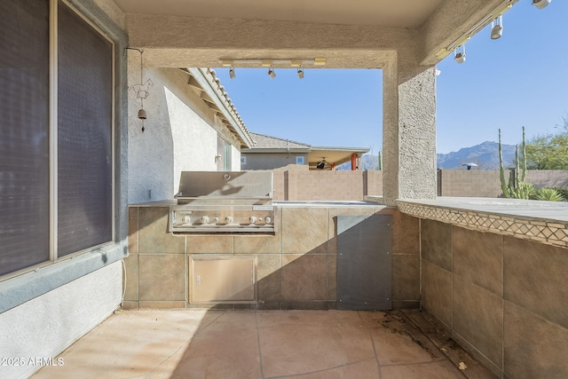 view of patio / terrace featuring exterior kitchen, fence, a mountain view, and a grill