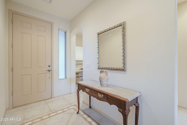 foyer entrance with arched walkways, a healthy amount of sunlight, visible vents, and light tile patterned floors