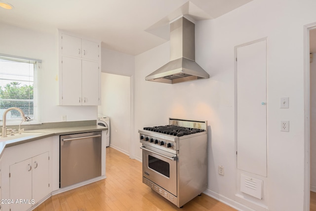 kitchen featuring extractor fan, appliances with stainless steel finishes, white cabinetry, light hardwood / wood-style floors, and sink