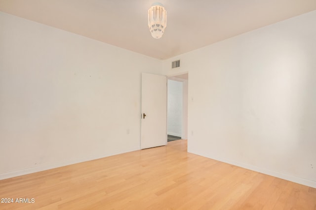 spare room featuring hardwood / wood-style flooring and an inviting chandelier