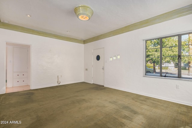 spare room with dark carpet and ornamental molding