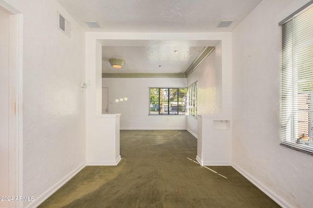 hall with dark carpet and crown molding