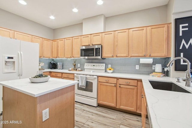 kitchen featuring white appliances, tasteful backsplash, a sink, and light brown cabinetry