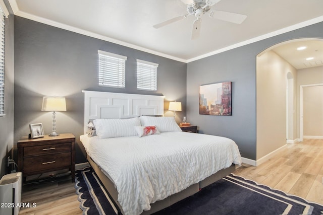 bedroom with arched walkways, light wood-style flooring, a ceiling fan, baseboards, and crown molding