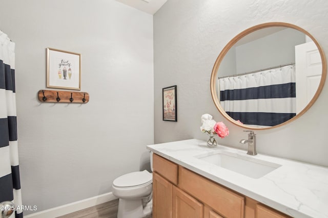 full bath with toilet, baseboards, wood finished floors, and vanity