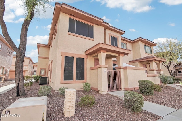 view of front of home with a fenced front yard, a gate, central AC, and stucco siding