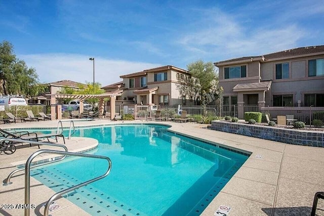 community pool with a patio area and fence