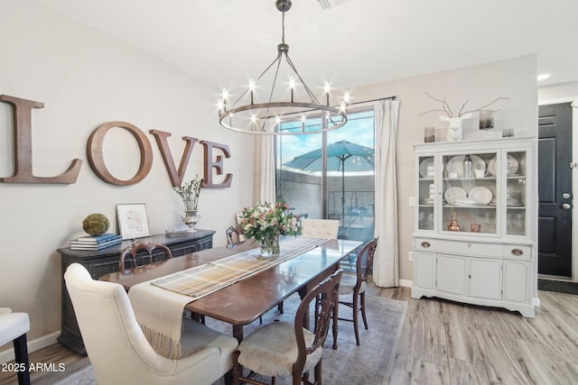 dining space featuring baseboards, light wood-type flooring, and an inviting chandelier