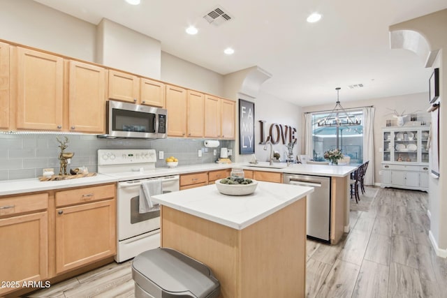 kitchen featuring a peninsula, visible vents, appliances with stainless steel finishes, and light brown cabinetry