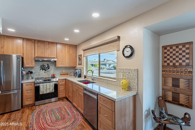 kitchen with dark wood-type flooring, sink, stainless steel appliances, light stone countertops, and backsplash