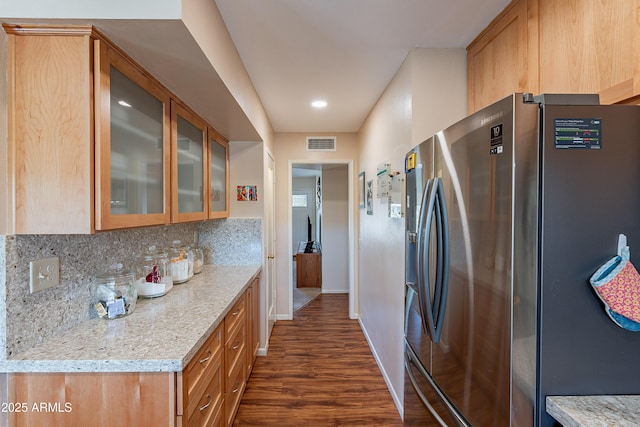 kitchen with light stone counters, dark wood-type flooring, stainless steel fridge with ice dispenser, and tasteful backsplash