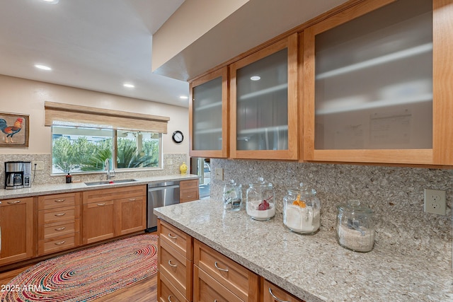 kitchen with sink, light stone counters, tasteful backsplash, wood-type flooring, and stainless steel dishwasher