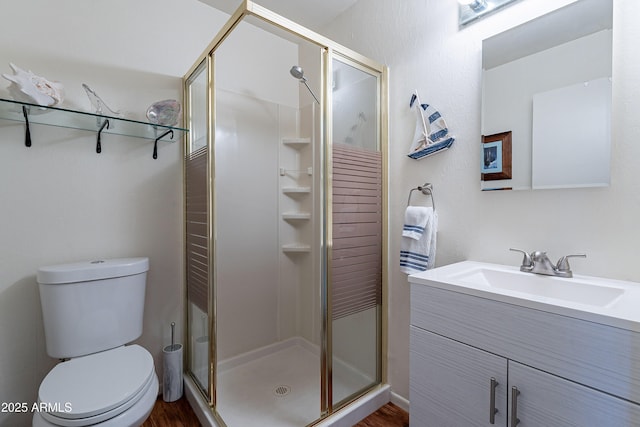 bathroom featuring vanity, a shower with shower door, and toilet