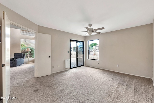 empty room with carpet flooring, a ceiling fan, and baseboards