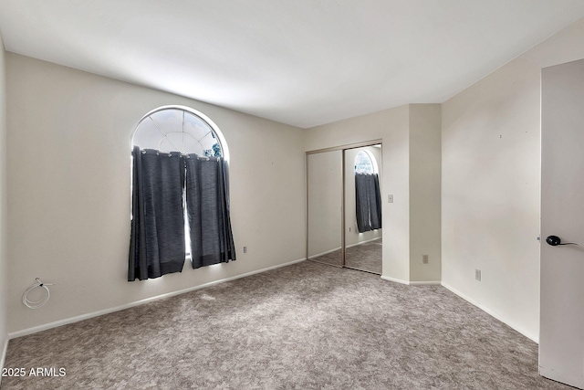 unfurnished bedroom featuring a closet, baseboards, and carpet flooring