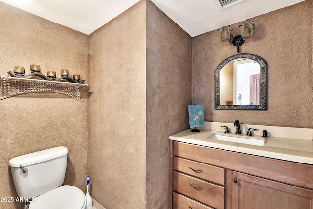 bathroom featuring visible vents, toilet, and vanity