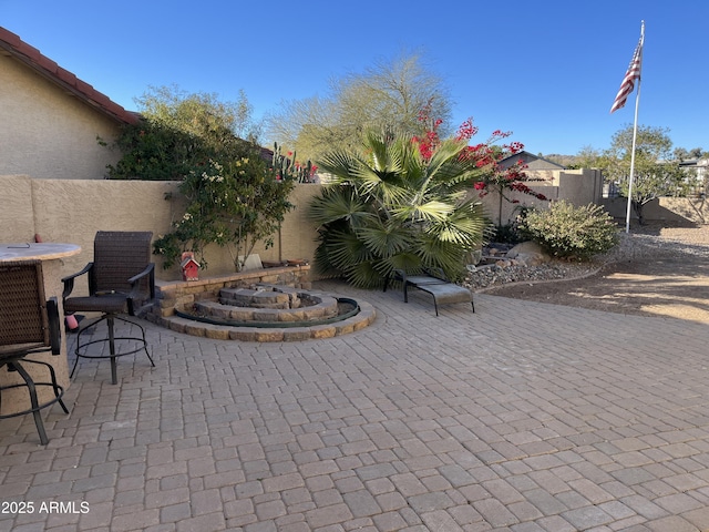 view of patio featuring an outdoor fire pit and fence