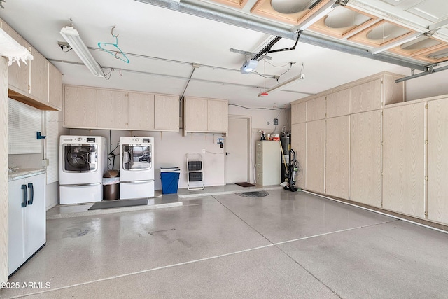 garage featuring washing machine and clothes dryer, heating unit, water heater, and a garage door opener