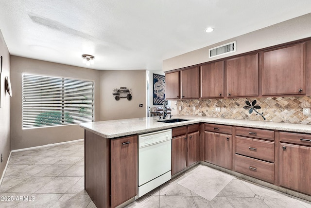 kitchen with visible vents, a peninsula, white dishwasher, a sink, and backsplash