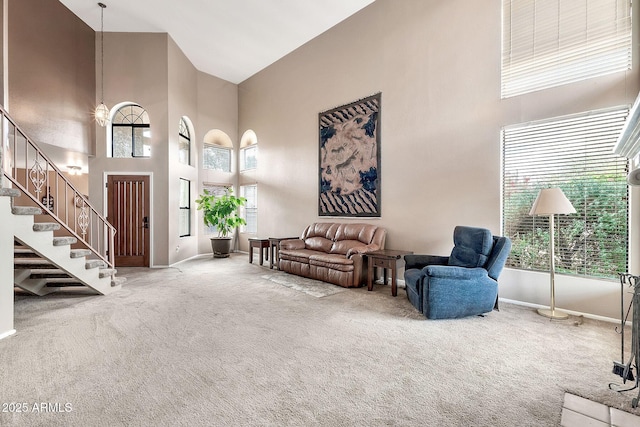 living area with stairway, baseboards, carpet, and a towering ceiling