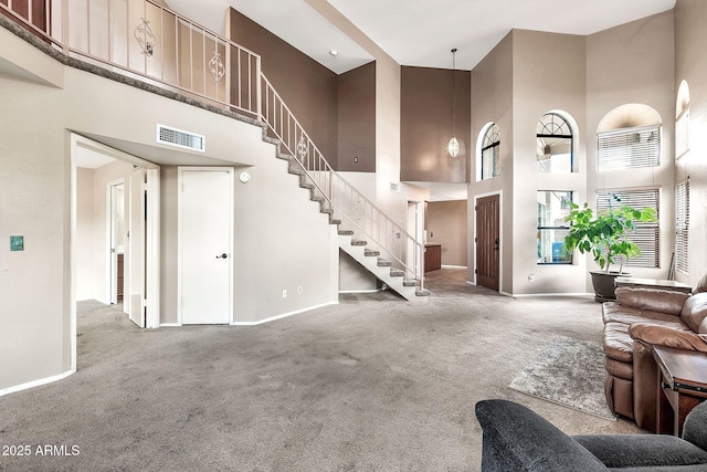 carpeted living area featuring visible vents, a high ceiling, stairs, and baseboards