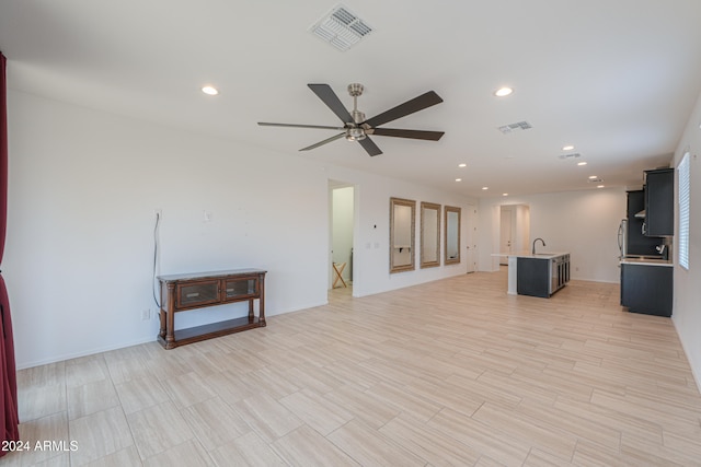 unfurnished living room with light hardwood / wood-style flooring, ceiling fan, and sink