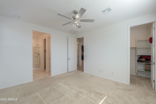 unfurnished bedroom with light carpet, ensuite bathroom, ceiling fan, a spacious closet, and a closet