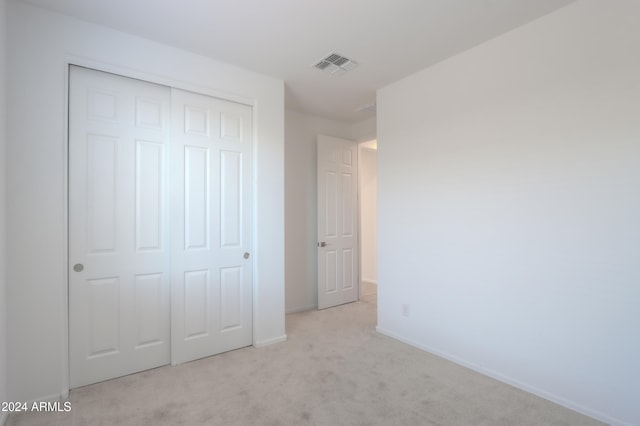 unfurnished bedroom with a closet and light colored carpet