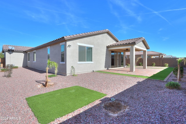 rear view of property featuring ceiling fan and a patio area